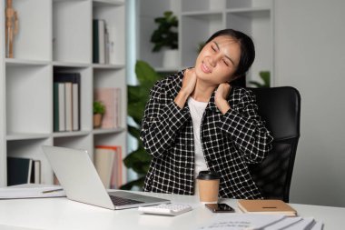 Yorgun bir kadın ofis çalışanı masasında dinlenmek için biraz zaman ayırır. İş yerinde yorgunluk ve stres gösterir..