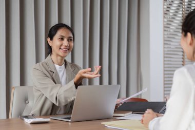 Modern bir ofis ortamında dizüstü bilgisayarlar ve belgeler kullanarak çalışma ve danışmanlık üzerine profesyonel iş ekibi.