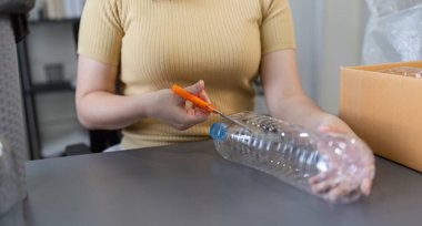 Genç kadın plastik şişeleri yaratıcı bir şekilde kullanışlı ev eşyalarına dönüştürüyor, sürdürülebilirliği ve çevre dostu yaşamı teşvik ediyor..