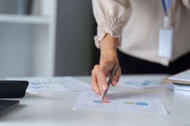 İş kadını, profesyonel çalışma ve analizleri vurgulayarak, modern ofis ortamında mali belgeleri incelemeye odaklandı.