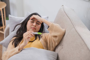 Bir kadın endişeyle hamilelik durumunu test kiti ile kontrol ederken evdeki kanepede yatıyor..