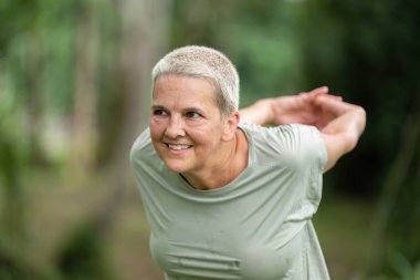 Huzurlu bir bahçede yoga pozu veren yaşlı bir kadın sağlığını, sağlığını ve aktif bir yaşam tarzını destekliyor..
