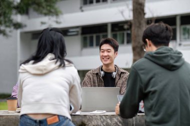 Öğrenciler sınavlara çalışmak, işbirliği yapmak ve açık hava üniversite kampüsü ortamında fikirleri paylaşmak için gruplar halinde toplanıyorlar..