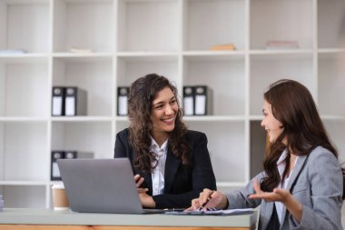 İş kadınlarının iş arkadaşlarıyla ortak bir tartışmaya girmesi, takım çalışması sergilemesi ve modern ofis ortamında profesyonel etkileşim.