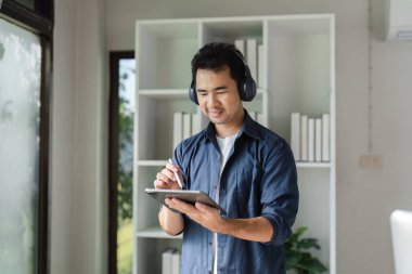 Grafik tasarımcısı modern ofis ortamında bir proje planlamak için bir tablet ve stil kullanır.