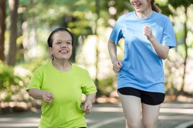 İki genç kadın, biri fiziksel farklılıklara sahip, açık havada birlikte egzersiz yapmaktan hoşlanıyorlar, kapsayıcılık ve dostluğu teşvik ediyorlar..