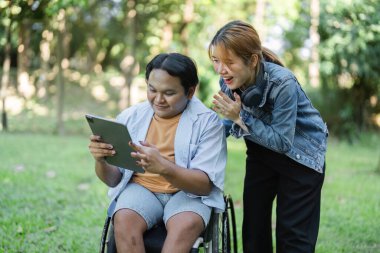 Tekerlekli sandalyedeki genç bir adam dışarıda iş arkadaşlarıyla işbirliği içinde çalışıyor, modern bir çalışma ortamında kapsayıcılık ve takım çalışması sergiliyor..