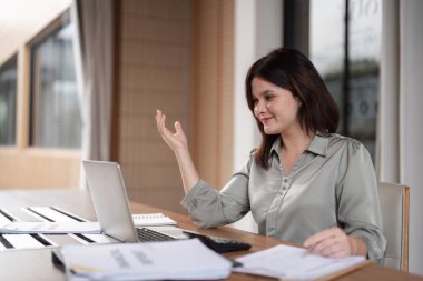 Çağdaş ofis ortamında dizüstü bilgisayar ve hesap makinesiyle çalışan bir muhasebeci.
