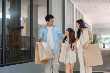 Neşeli bir aile alışveriş gününün tadını çıkarır. Canlı bir şehir ortamında samimi gülüşmeler ve beraberlik anları yakalar..