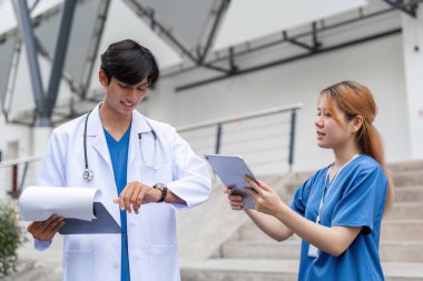 İki sağlık uzmanı, hastane ortamında hasta bakımında takım çalışması ve iletişim konusunda işbirliği yapmaktadır..