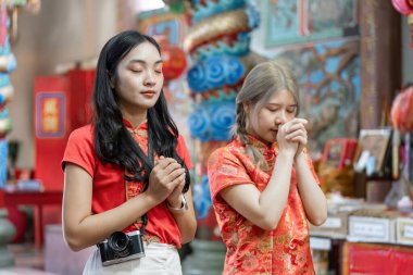 Geleneksel kıyafetli iki kadın Çin Yeni Yılı 'nda bir tapınakta kültürel saygıyı ve kutlamayı yansıtan bir tapınağa girerler..