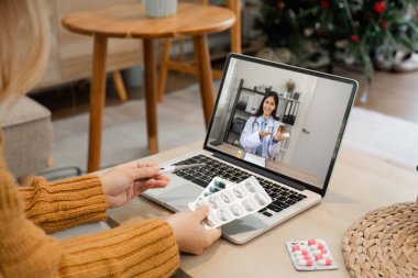 Bir kadın doktor, ev ortamında modern teletıp görüntülerini gösteren bir video aracılığıyla çevrimiçi sağlık tavsiyeleri sunar..