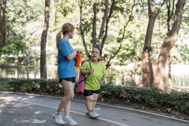 Minyon engelli bir kadın, destekleyici bayan arkadaşıyla parkta antrenman yapmaktan zevk alıyor. Kapsamlılık ve arkadaşlığı teşvik ediyor..
