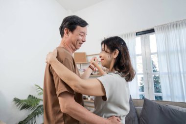 Emekli bir çift, altın yıllarında aşk ve mutluluğu kutlamak için oturma odalarında neşeli bir dans eder..