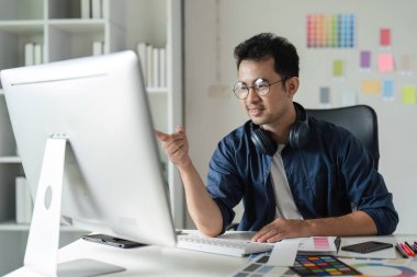 Modern bir ofis ortamında dijital araçlar ve renk örnekleri kullanarak, grafik tasarımcısı web sitesi tasarımına odaklandı.