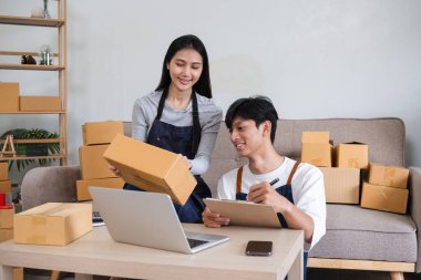 Bir çift evlerinde online bir iş yürütmek için işbirliği yapıyor, sipariş alıyor ve sevkiyat için ürün paketliyorlar..