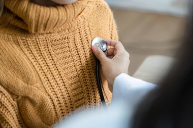 Bir doktor, bir hastaya sağlık kontrolü yapmak için steteskop kullanır, profesyonel sağlık ve tıbbi muayeneyi vurgular.