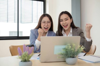 İki kadın muhasebeci finansal grafikler üzerinde birlikte çalışıyorlar, modern ofis ortamında verileri analiz ediyorlar, takım çalışması ve profesyonel işbirliği sergiliyorlar..
