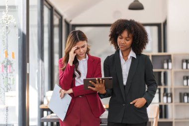 İş kadını, modern ofis ortamındaki bir meslektaşıyla görevleri tartışırken iş yerinde stres yaşıyor..