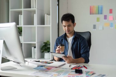 Modern ofis ortamında dijital araçlar ve renk paletleri kullanarak, grafik tasarımcısı web sitesi tasarımına odaklandı.