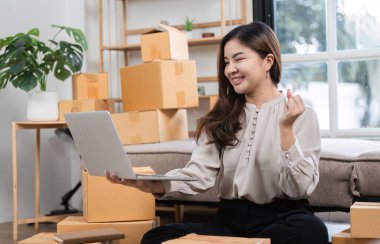 Çevresi kargo kutularıyla çevrili ve dizüstü bilgisayar kullanan genç bir girişimci..