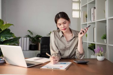 Çağdaş bir ofis ortamında evrak işleriyle uğraşırken, genç bir muhasebecinin birden fazla görevi vardır..