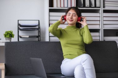 Modern ofiste kulaklıkla dinlenen Asyalı kadın, rahatlama kavramı..