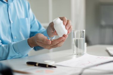 Sağlık ve kendine bakmanın önemini vurgulayarak, evde hasta hissederken ilaç alan bir kişi.