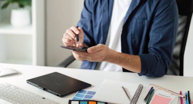 Yaratıcı projeler için dijital araçlar ve renk örnekleri kullanarak çağdaş bir stüdyo ortamında grafik tasarımcısı.