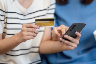 Modern aile yaşam tarzı ve teknolojisini ön plana çıkaran akıllı telefon ve kredi kartı kullanan bir anne ve çocuk mağazası..