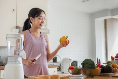 Modern bir mutfakta genç bir kadın meyve püresi hazırlıyor, sağlık, sağlık ve besleyici bir yaşam tarzını ön plana çıkarıyor..