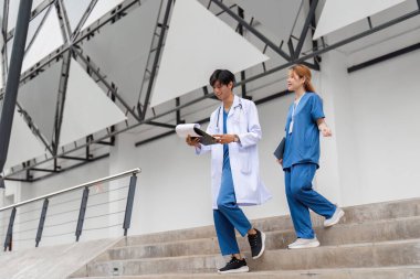 İki sağlık çalışanı hastane merdivenlerinden inerken hasta bakımıyla ilgili detaylı bir tartışmaya giriştiler..