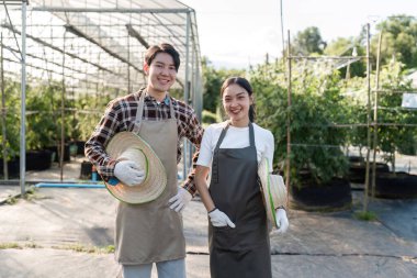 Kenevir bahçesinde birlikte çalışan bir çift modern bir serada sürdürülebilir bahçıvanlık uygulamaları sergiliyor..