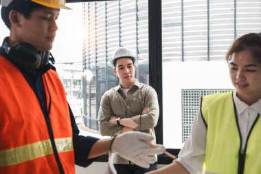 İnşaat alanında mühendis ekibi tartışması sırasında ayakta duran yakışıklı genç mühendis..