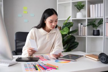 Grafik tasarımı alanında çalışan kadın tasarımcı tabletler ve bilgisayar tasarımları üzerinde çalışmak için renkler seçin..