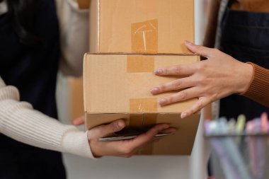 Birlikte koordine eden iki kadın dikkatle paketlenmiş kutuları teslim ediyor ve online malı etkili bir şekilde teslim etmede takım çalışmasını vurguluyor..