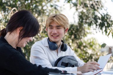 High school students gather outdoors to study and collaborate on assignments, fostering teamwork and learning. clipart