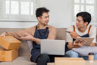 Adanmış bir LGBT çifti çevrimiçi işleri hakkında bir tartışma içinde, ürün ambalajlarını analiz ediyorlar ve rahat bir ev ortamında fikirleri paylaşıyorlar..