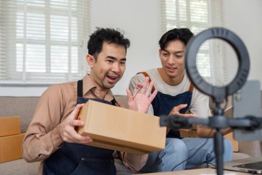 İki hevesli sosyal medya pazarlamacısı şık bir ev ofisinde canlı yayın sırasında ürünleri açıyor ve çevrimiçi izleyicileriyle etkileşime geçiyorlar..