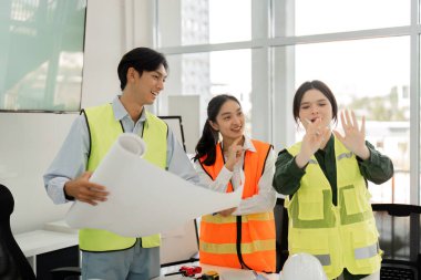 Aralarında bir mimar, mühendis ve tasarımcının da bulunduğu çeşitli bir inşaat ekibi, çağdaş bir ofis alanının planları üzerinde işbirliği yaparak yaratıcılığı ve takım çalışmasını teşvik eder..