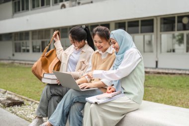Üniversite kampüsünün dışında bir dizüstü bilgisayarda işbirliği içinde çalışan çeşitli bayan öğrencilerden oluşan bir grup, dostluk ve akademik coşku sergiliyor..