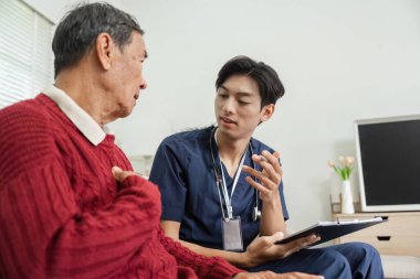 İlgili bir hemşire, yaşlı bir adamın sağlık durumu hakkında düşünceli bir konuşma yapar ve destekleyici bir ev ortamında net bir iletişim sağlar..