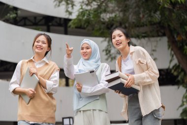 Üç farklı kız öğrenci akademik başarılarını dışarıda sevinçle kutluyor, kitaplarını tutarken gülümsüyor ve gelecekle ilgili planlarını tartışıyorlar..