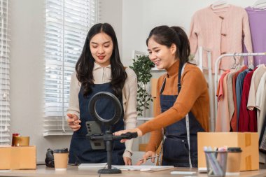 Çevrimiçi bir butikte ürünleri satmak için işbirliği yapan çeşitli bir çift, dijital bir platform aracılığıyla müşterilerle iletişim kuruyor..