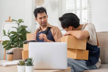 Çevrimiçi iş stratejilerine odaklanan, modern yaşam alanlarında paketlenmiş kutularla çevrili iki adam..