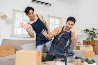 Canlı yayın sırasında eğlenen iki hevesli sosyal medya pazarlamacısı paketler arasında rahat bir evde otururken ürünlerini sergiliyorlar..