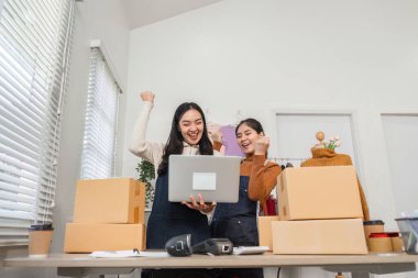 İki farklı perakende işçisi, envanteri yönetirken ve mağaza ortamında dizüstü bilgisayar kullanırken başarıyı neşeyle kutluyorlar..