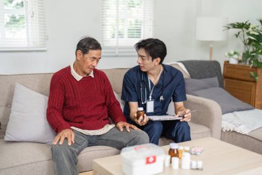 Bir hemşire, yaşlı bir hastayla kanepede tedavi planını dikkatlice tartışıyor ve rahat bir oturma odasında rahatlık ve destek sağlıyor..