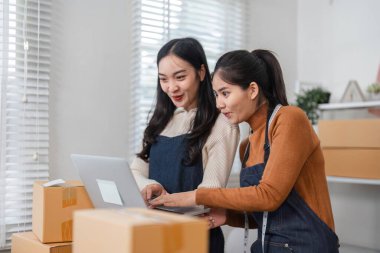 İki farklı kadın e-ticaret çalışanı, bir perakende mağazasında envanter yönetimi ve sipariş işleme için dizüstü bilgisayar kullanıyor..