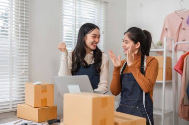 Perakende mağazasında çalışırken başarılı satış ve başarıları kutlayan iki farklı kadın e-ticaret çalışanı.